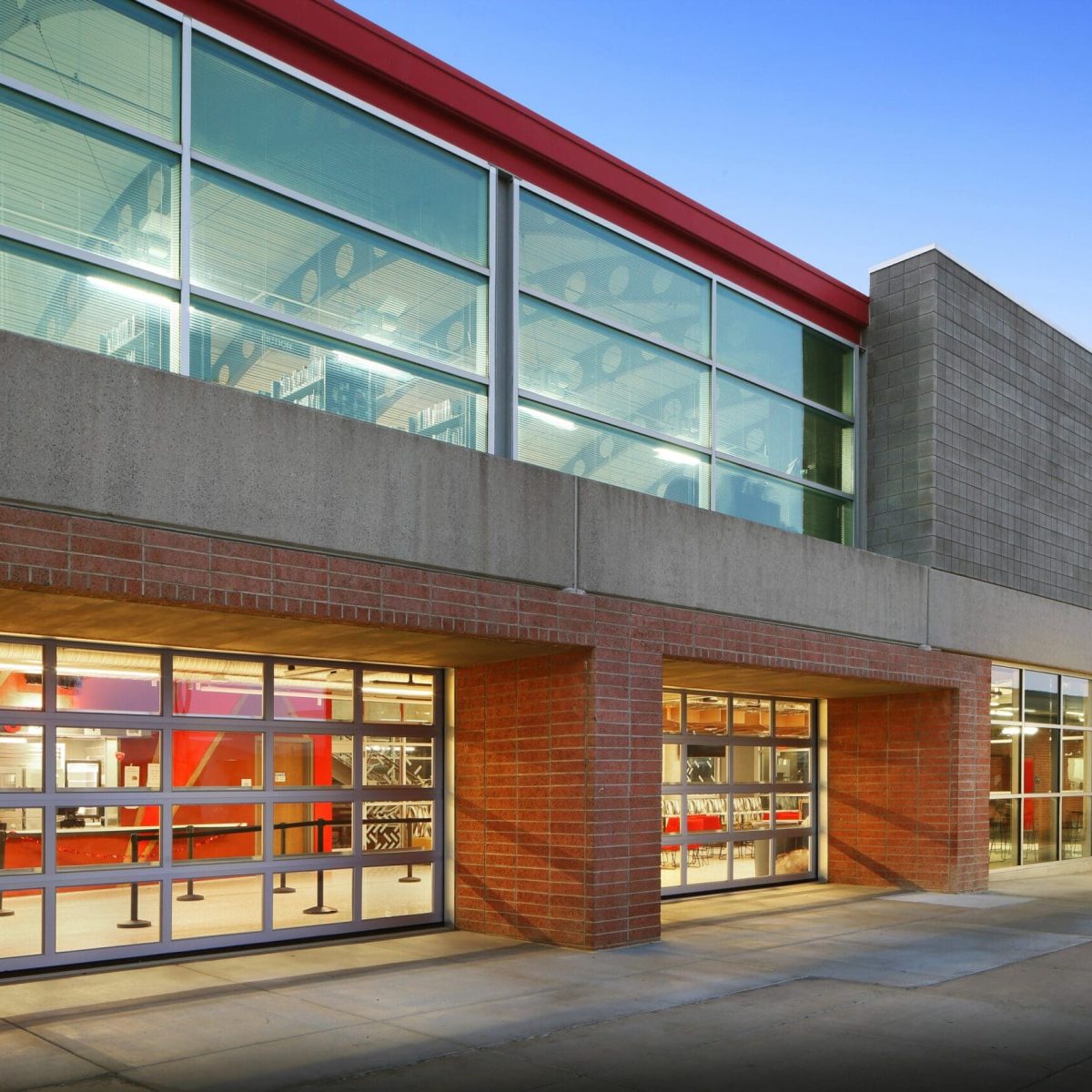 Exterior of a modern commercial building with large glass windows and a mix of brick and concrete walls, reminiscent of an innovative education center, all under a clear blue sky.
